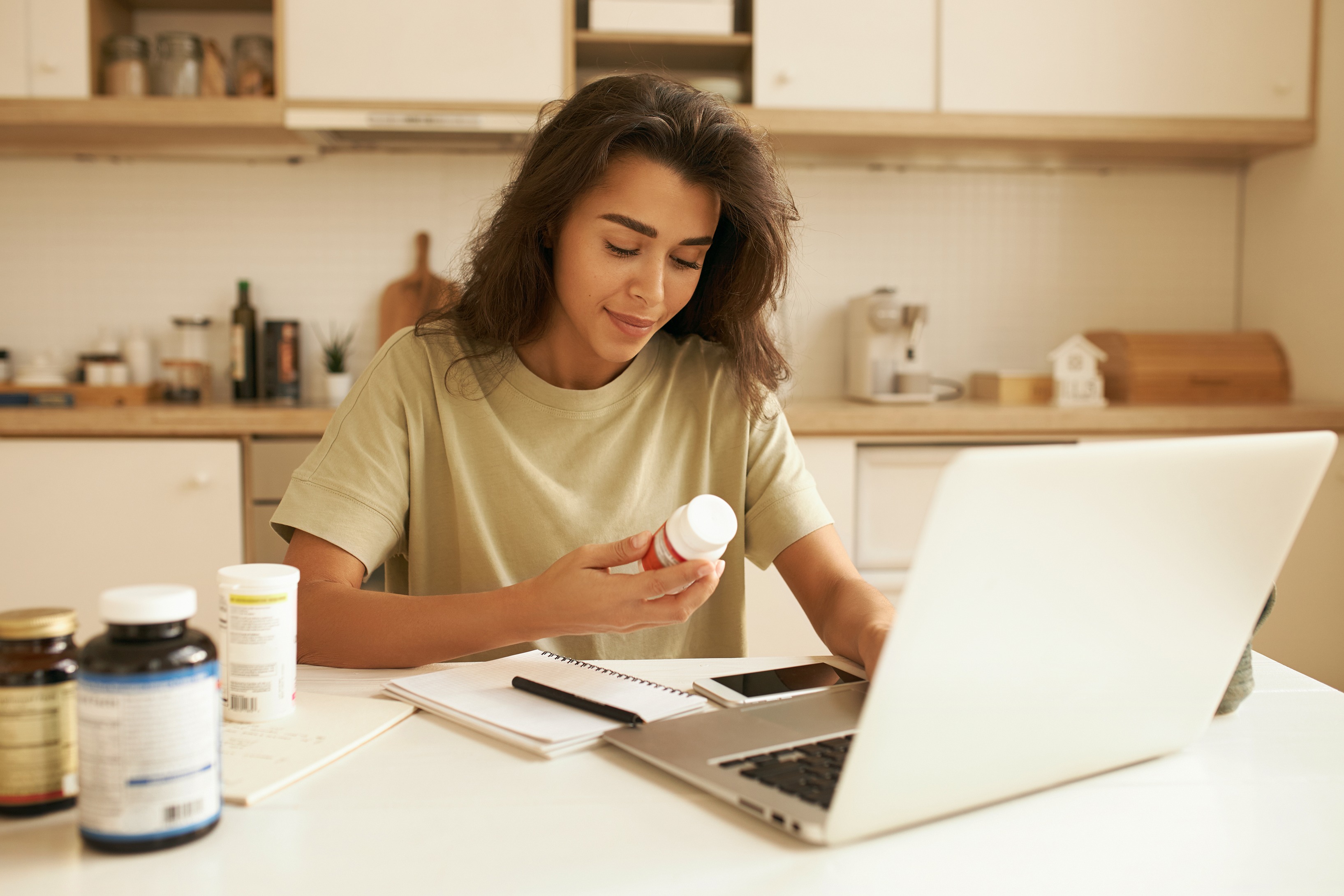 Woman comparing supplement labels while researching products online.